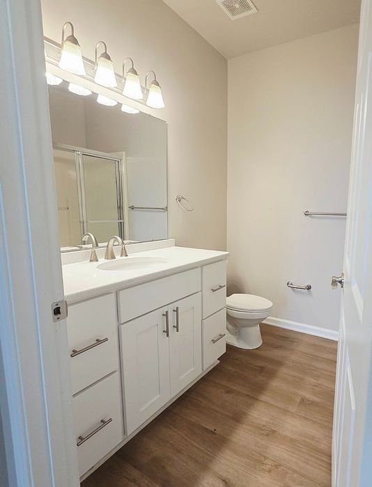 Elegant bathroom with modern fixtures, bright lighting, and sleek wooden flooring offering a refreshing space.