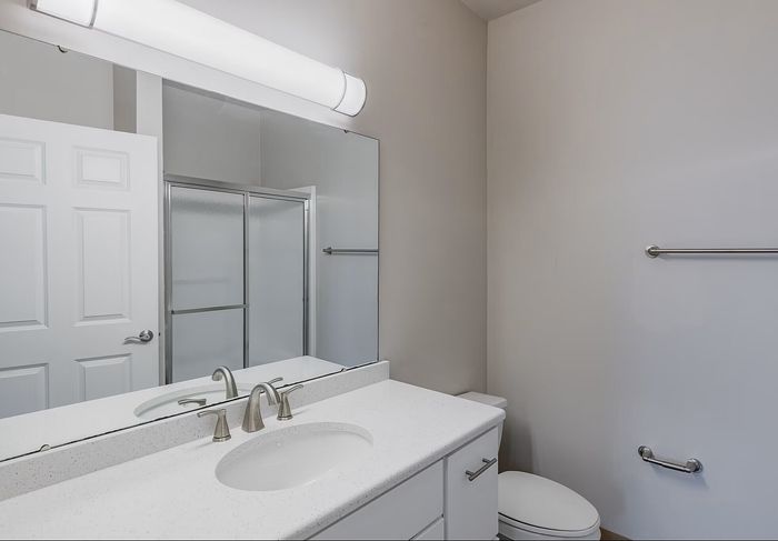 Modern bathroom featuring a sleek vanity with under-sink storage, and a spacious glass-enclosed shower.