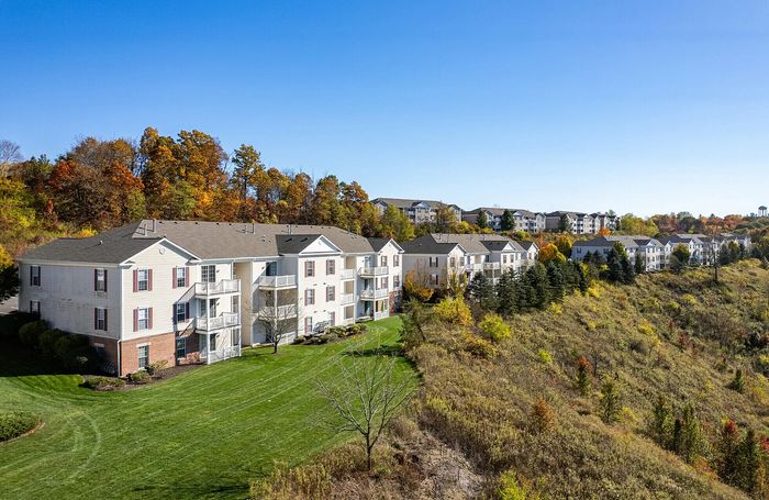 Charming community nestled against a a lush backdrop, featuring inviting balconies and manicured lawns.