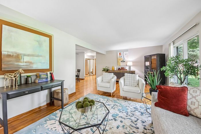 Bright and inviting living area with elegant decor, featuring comfortable seating, modern art, and lush greenery, ideal for relaxation and entertainment.