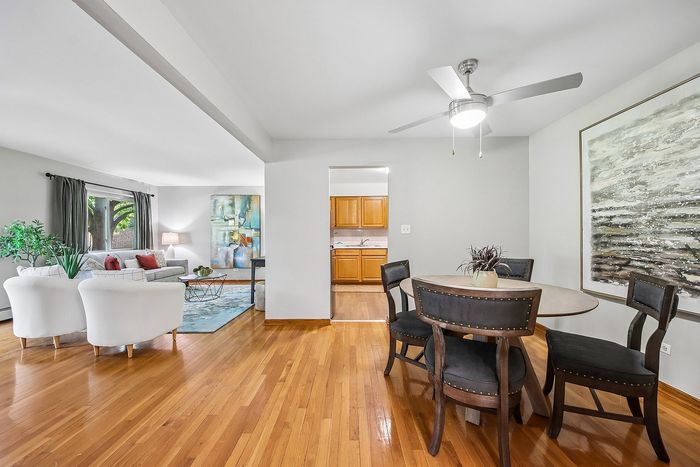 Bright, open-plan living and dining area with stylish hardwood floors, cozy seating, and modern decor, leading to a charming kitchen space.