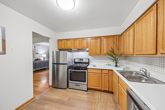 Charming kitchen with modern stainless steel appliances, warm wooden cabinets, and a cozy open layout leading to a stylish living area.