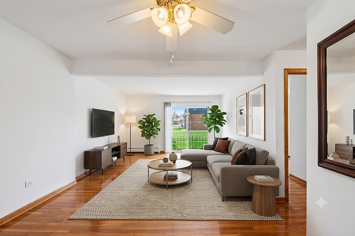 Bright living room with elegant ceiling fan, cozy sectional sofa, modern decor, and large window offering lush views.