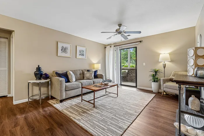 Inviting living room with stylish decor, featuring a cozy sofa, wooden coffee table, and sliding glass door leading to a charming patio.