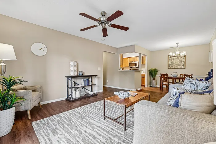 Charming open-plan living area featuring elegant decor, cozy seating, modern ceiling fan, and stylish dining space adjacent to a sleek kitchen.