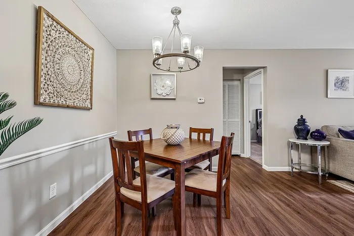 Charming dining area with elegant wood furniture, artistic wall decor, and a modern chandelier, perfect for cozy gatherings.