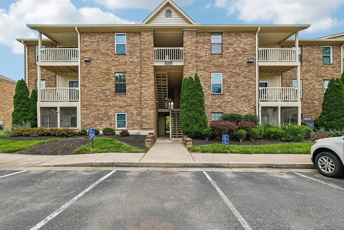 Charming brick apartment building with inviting balconies, lush landscaping, and convenient parking in a peaceful neighborhood setting.