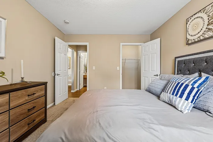 Inviting bedroom with modern decor featuring a cozy bed, stylish wooden dresser, and neutral walls, perfect for relaxation.
