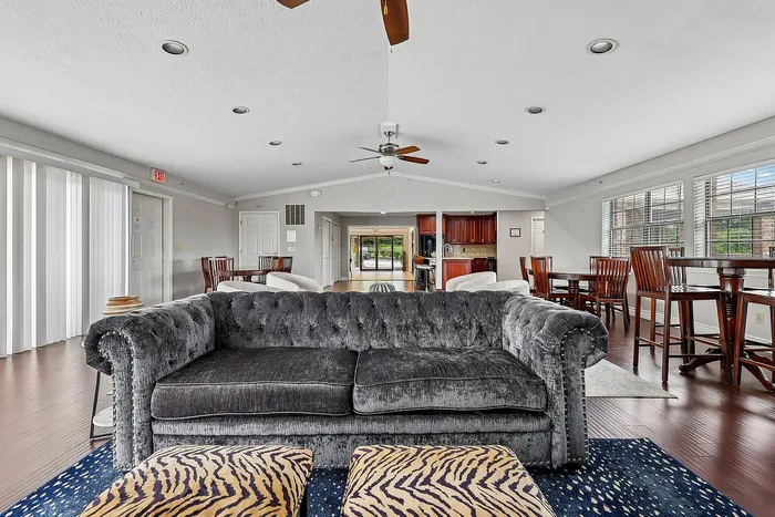 Elegant open-concept living area featuring a plush gray sofa, stylish wooden dining sets, and a modern kitchen with an inviting ambiance.