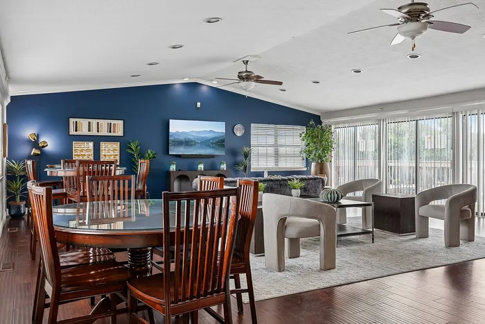 Elegant open-concept living space featuring sleek wooden dining furniture, modern decor, and large windows with abundant natural light.