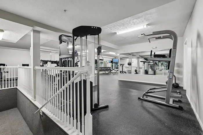 Modern apartment gym with state-of-the-art fitness equipment, mirrored walls, and sleek design.