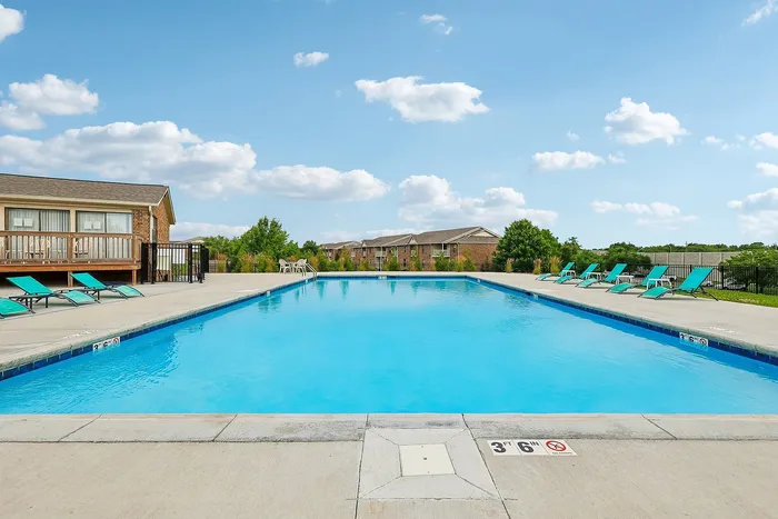 Inviting outdoor pool area with lounge chairs, clear blue water, and a sunny sky, perfect for relaxation and enjoyment.