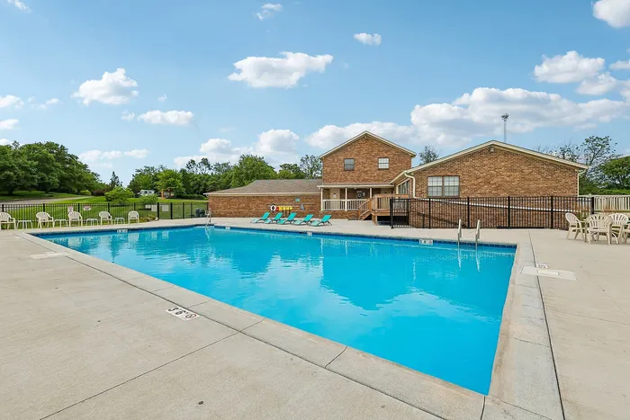 Inviting apartment complex showcasing a sparkling outdoor pool, surrounded by stylish lounge chairs and scenic greenery.
