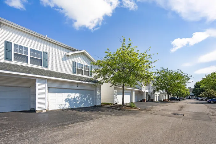 Charming suburban apartments with attached garages and vibrant trees lining a quiet street.