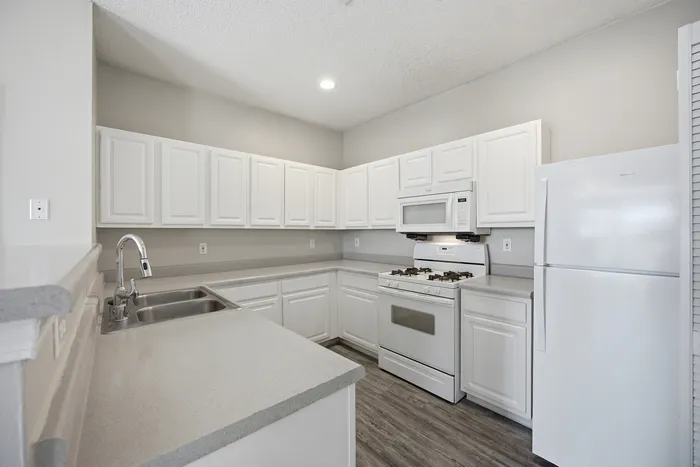 Modern kitchen with sleek white cabinetry, stainless steel sink, and stylish countertops, offering a bright and inviting cooking space.
