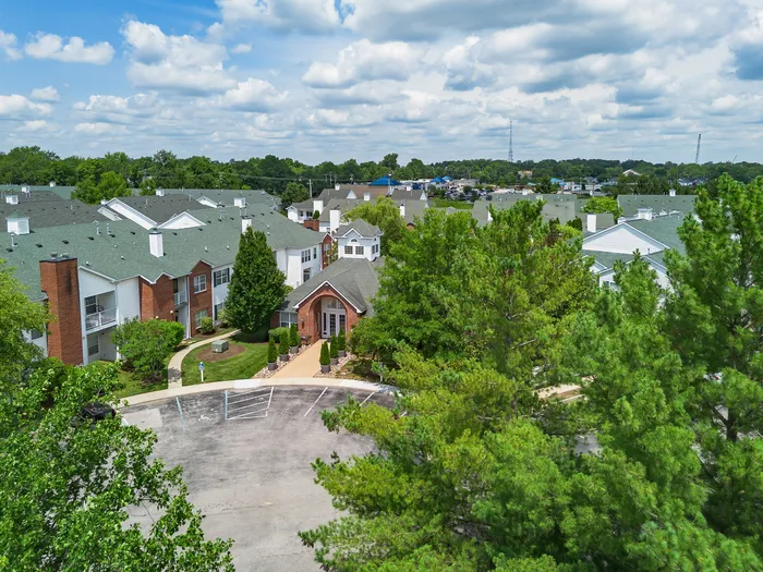 Charming residential community with brick and white exterior buildings surrounded by lush greenery and picturesque skies.