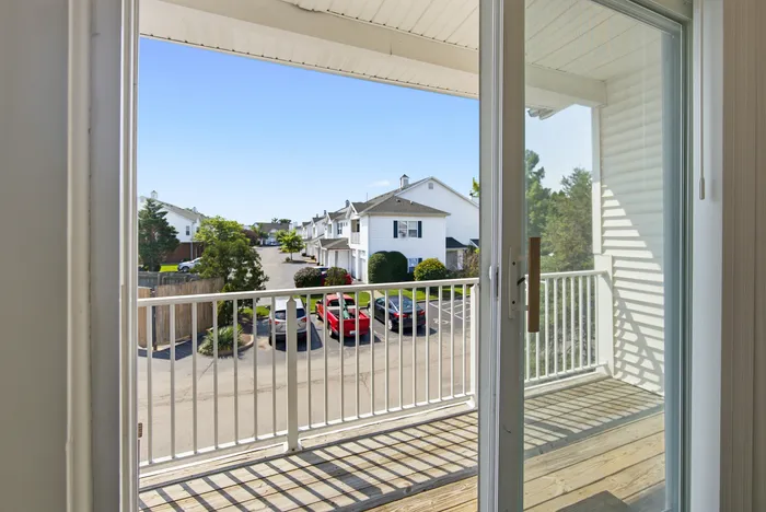 Charming apartment balcony with serene view of quiet neighborhood street and clear blue sky.