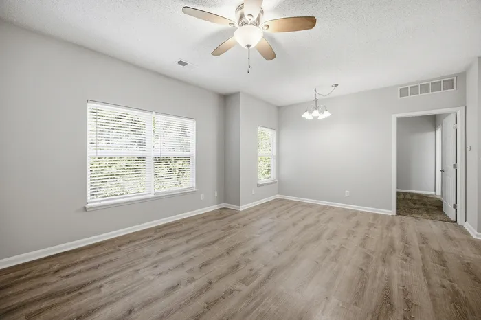 Bright and spacious room with elegant wood flooring, large windows, and modern ceiling lights.