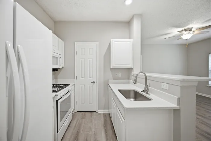 Modern kitchen with sleek white cabinetry, stainless steel appliances, and elegant countertops in a bright, open layout.