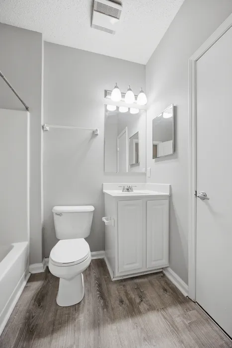 Elegant bathroom with modern fixtures, featuring a sleek vanity, chic mirror, and stylish wood flooring, perfect for a contemporary apartment.