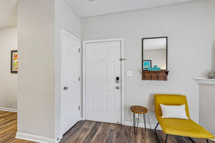 Chic apartment entryway with modern decor featuring minimalist furnishings, an inviting yellow lounge chair, and stylish wood accents.
