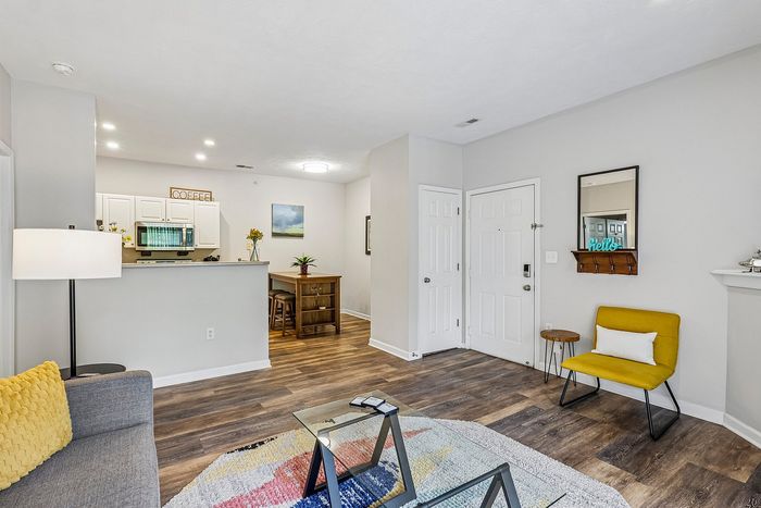 Inviting modern living room with cozy decor, featuring elegant hardwood floors, a stylish kitchen nook, and vibrant seating.