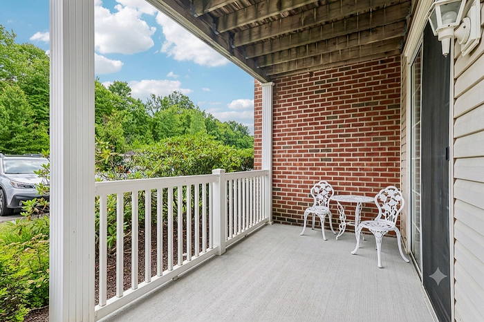 Charming outdoor patio with elegant white furniture, surrounded by lush greenery and a scenic view. Perfect for relaxing moments.