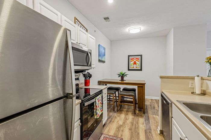 Chic kitchen with stainless steel appliances, cozy dining area, and vibrant artwork, offering modern style and functionality.