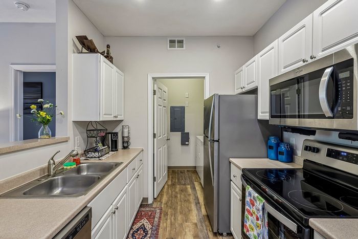 Contemporary kitchen with sleek stainless steel appliances, elegant white cabinetry, and a cozy ambiance perfect for culinary adventures.
