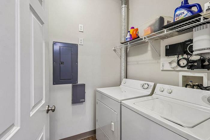 Modern laundry room with high-efficiency washer and dryer, ample shelving, and organized storage space.