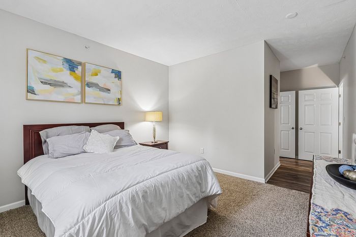 Bright and inviting bedroom with elegant decor, featuring a plush bed, abstract wall art, and warm ambient lighting.