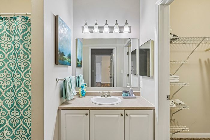 Chic and modern bathroom with elegant lighting, a stylish vanity, and a vibrant teal shower curtain.
