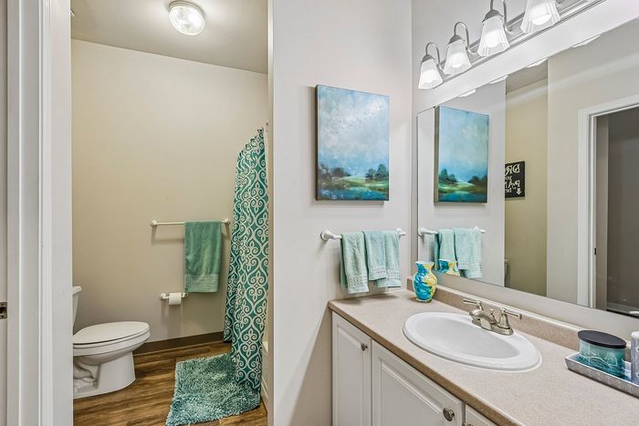 Inviting bathroom with modern fixtures, elegant artwork, and vibrant teal accents.