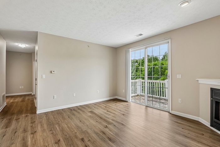 Bright and inviting living room with modern wood flooring and large sliding glass doors opening to a scenic balcony view.