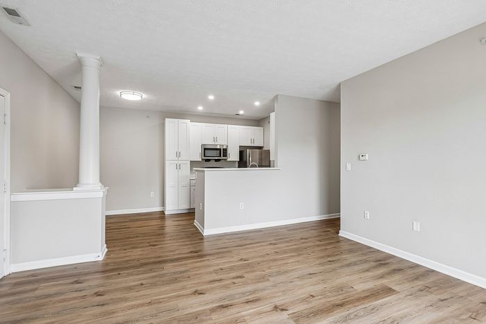 Modern open-concept apartment showcasing elegant flooring, sleek white kitchen cabinets, and ample natural light.