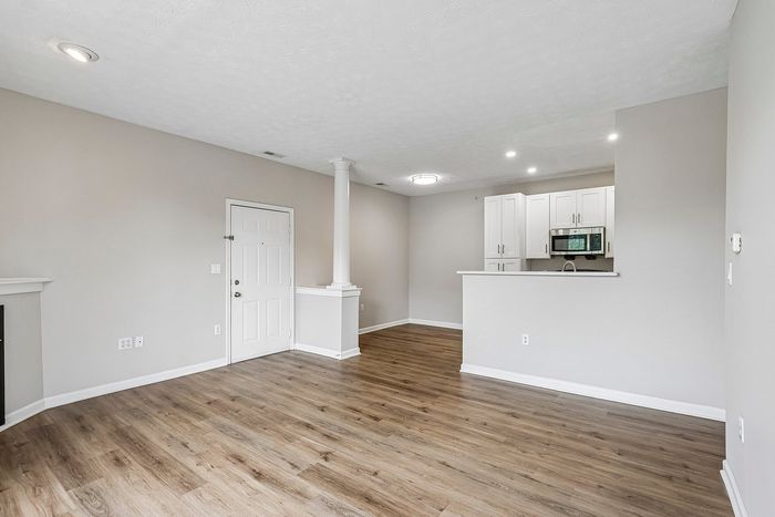 Bright and airy living space with elegant wooden flooring, modern kitchen, and contemporary lighting.