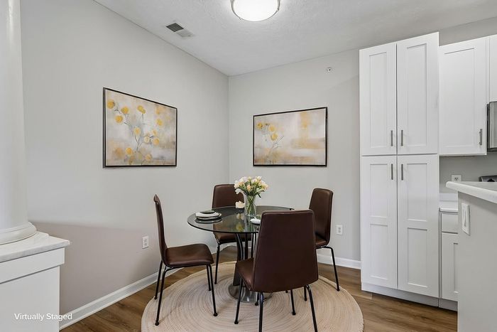 Inviting dining area with chic glass table, modern brown chairs, and elegant floral art on soft-toned walls, creating a cozy and stylish ambiance.
