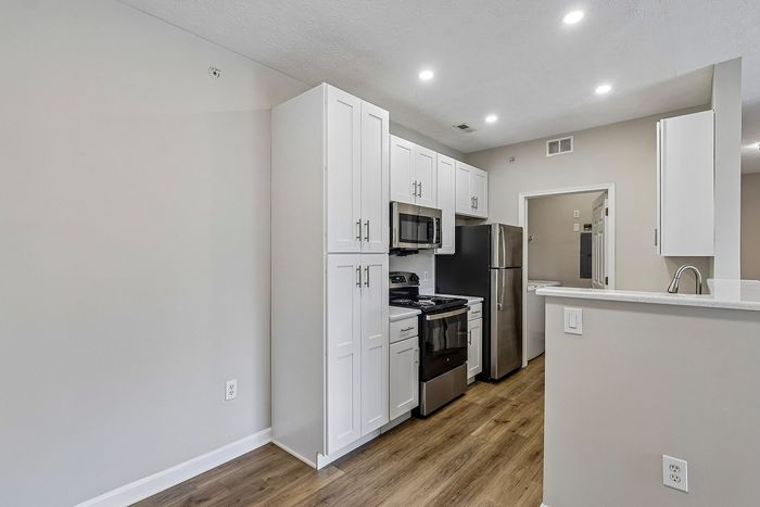 Modern kitchen with sleek stainless steel appliances, elegant white cabinetry, and polished wood flooring.