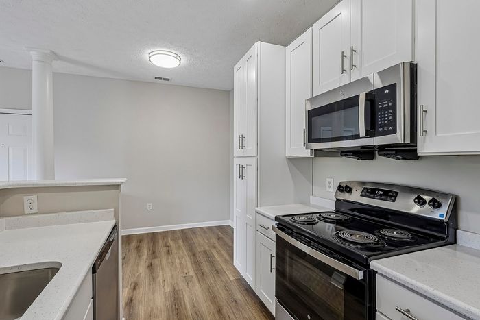 Modern kitchen with sleek stainless steel appliances, white cabinetry, and elegant hardwood flooring.