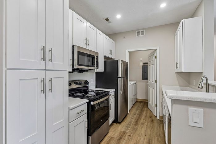 Contemporary kitchen with sleek white cabinets, stainless steel appliances, and modern lighting, offering a stylish and functional space.