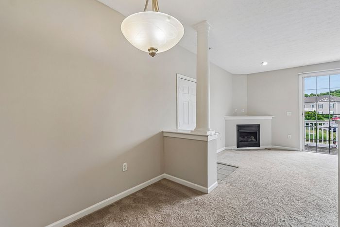 Inviting living area with elegant column details, cozy fireplace, and bright natural light from large sliding glass doors.