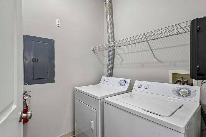 Modern laundry room featuring a sleek washer and dryer with ample overhead storage space.