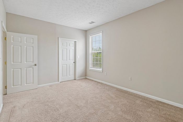 Bright and spacious room with plush carpet, modern neutral walls, and large window inviting natural light.