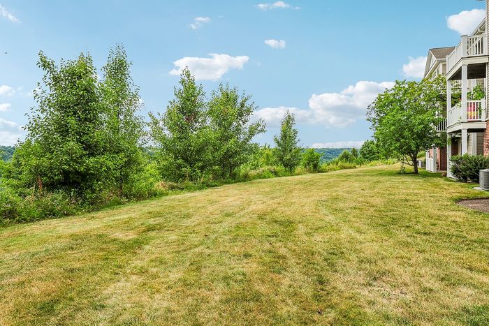 Serene landscape view from a charming apartment complex, featuring lush green lawns and vibrant trees under a clear blue sky.