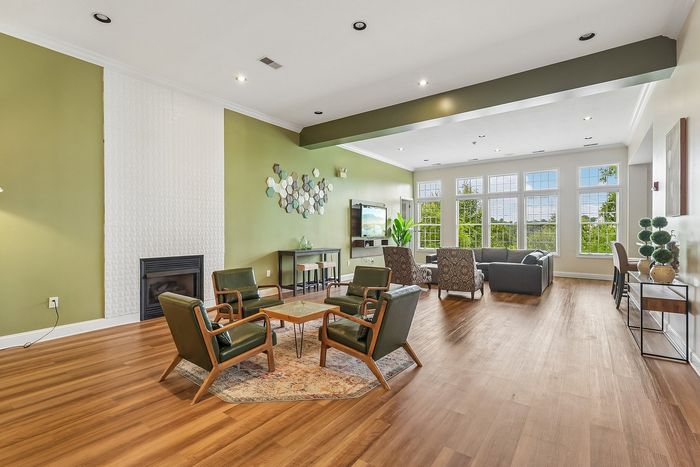 Chic living room with elegant green accents, cozy seating area, large windows offering scenic views, and stylish hardwood floors.