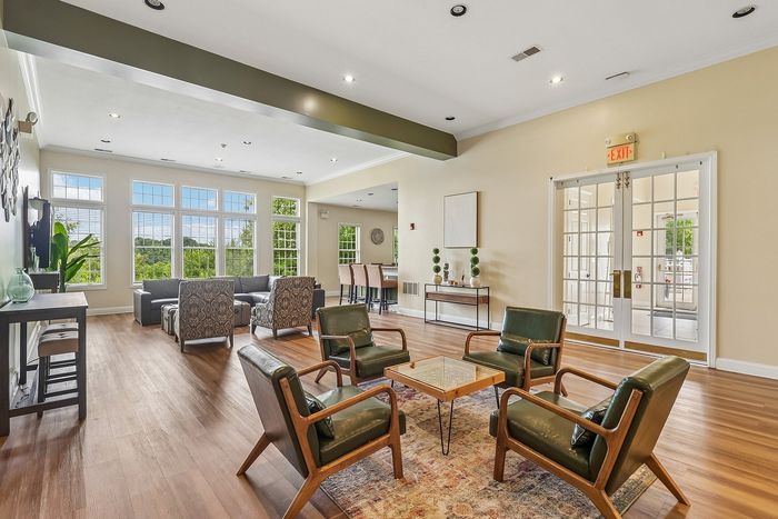 Bright and inviting living area featuring large windows, elegant seating, and contemporary decor in a spacious open-concept apartment.