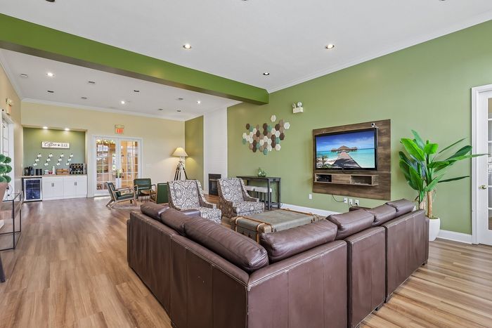 Inviting community lounge with plush leather seating, vibrant green accent walls, and a modern entertainment center.