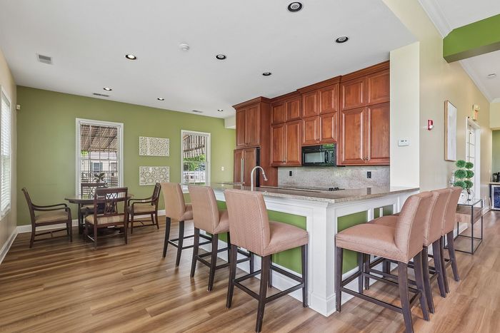 Inviting modern kitchen and dining area featuring warm wooden cabinets, vibrant green walls, and elegant hardwood floors.