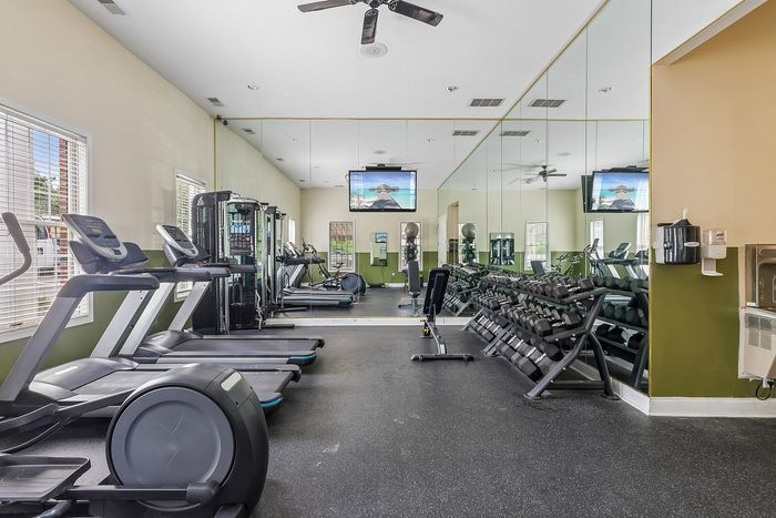 Bright and spacious apartment fitness center featuring state-of-the-art equipment, free weights, and inspiring mirrored walls.