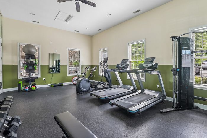 Bright and modern fitness center equipped with treadmills, exercise bikes, free weights, and resistance training station.